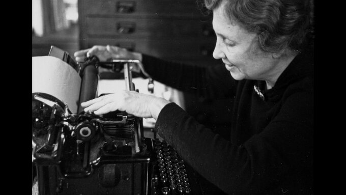 A black and white portrait of Helen Keller working on a typewriter.