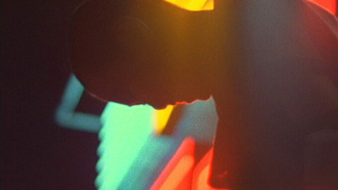 A sihlouette of a child's head and bright neon lights in the background.
