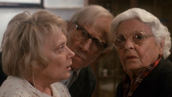 Still from Tell Me A Riddle featuring two two older women and a man looking surprised or concerned