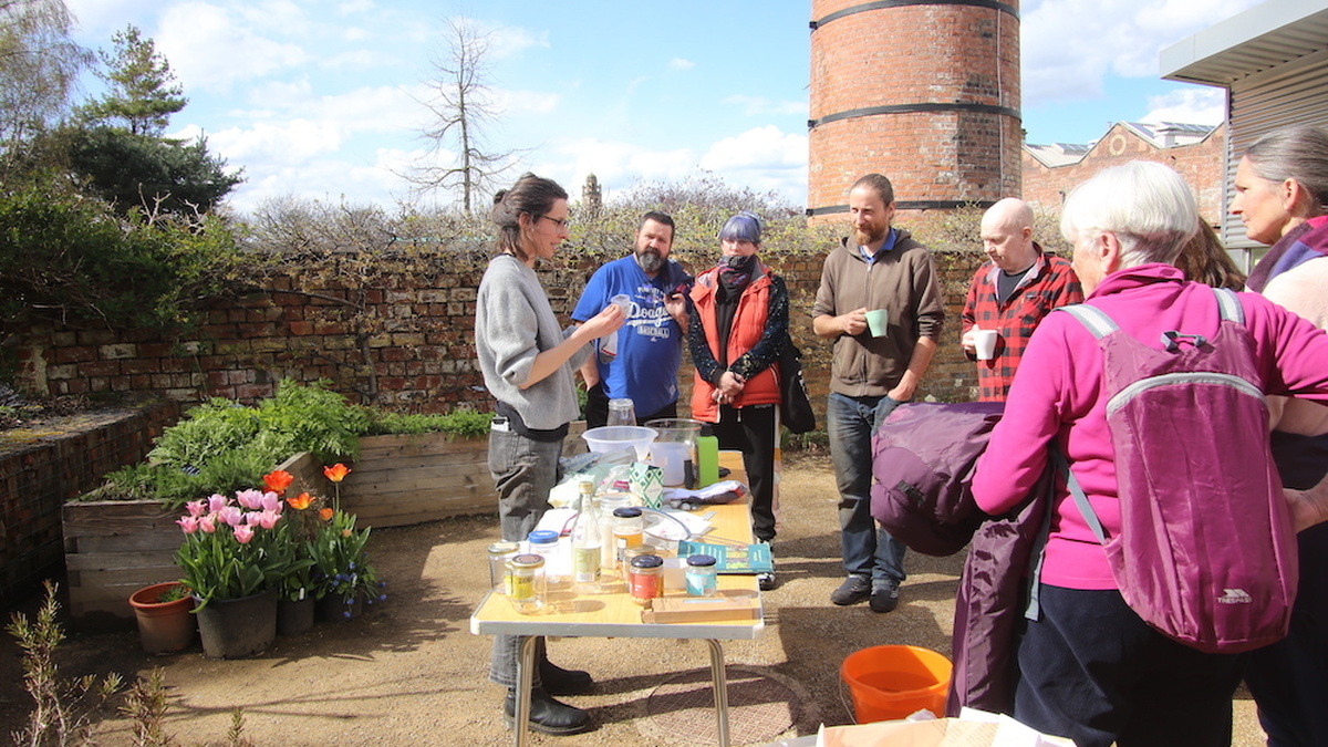 Louise King, speaking to a group of people about seed innoculants, outdoors at The Hidden Gardens