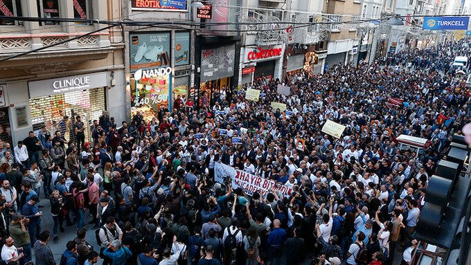 A crowd of people marching in a street holding banners, seen from above.