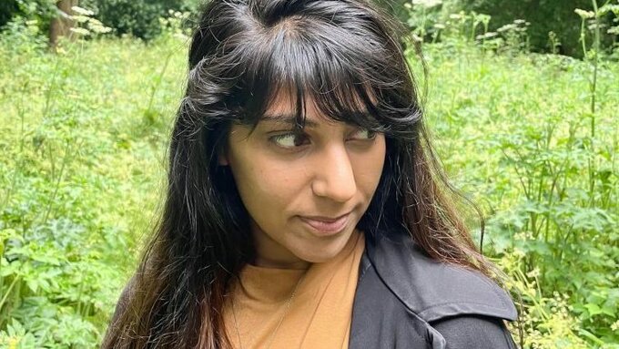 Alycia Pirmohamed standing in a sunny green glade, surrounded by vegetation.