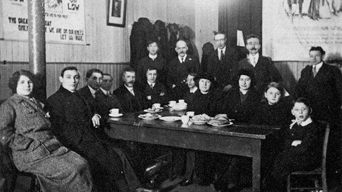 A black and white photograph of people sitting around a table at a Glasgow Anarchists meeting in 1915.