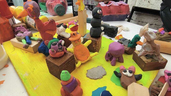 A table full of sculptures made by children out of brightly coloured clay