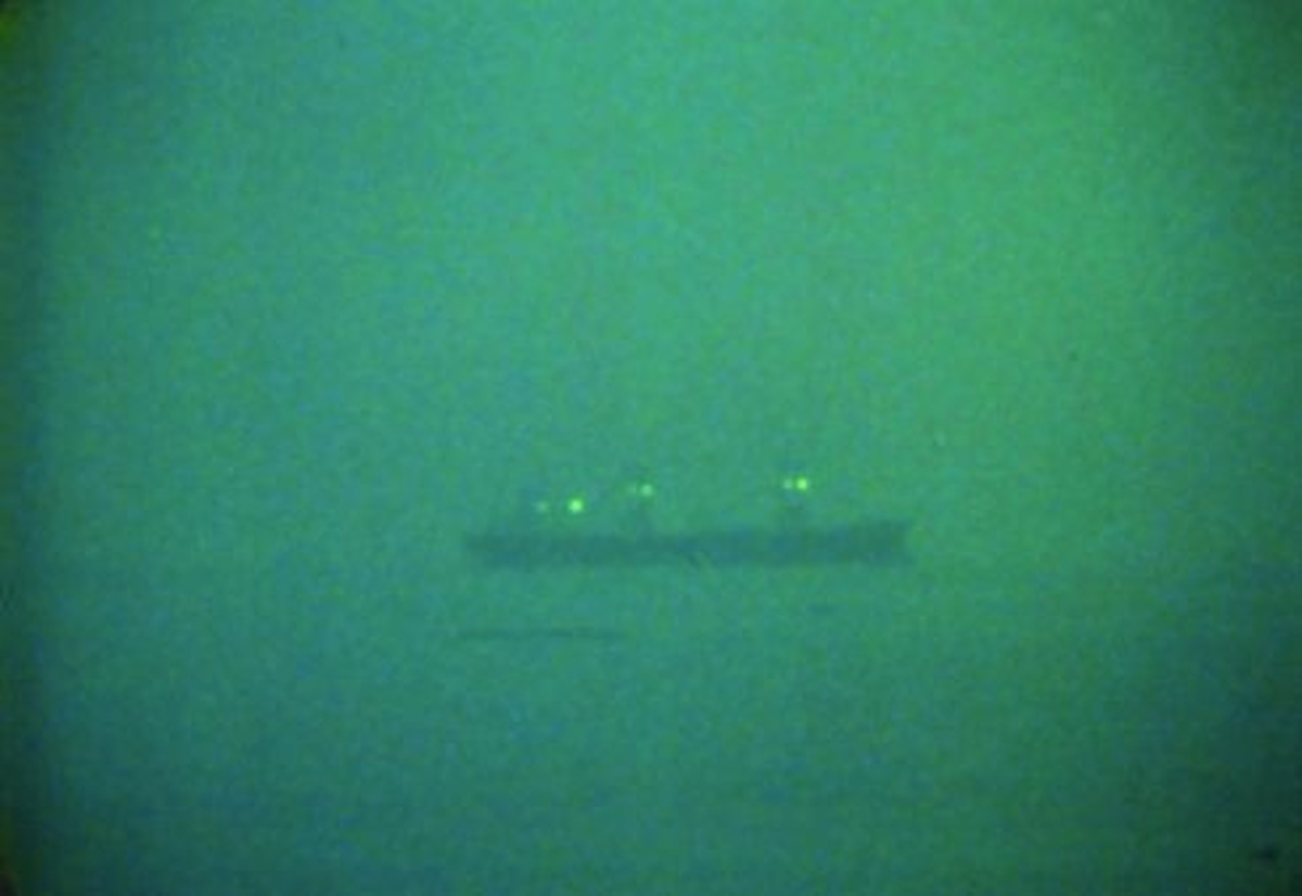 A dark grainy image of a tanker on the horizon.