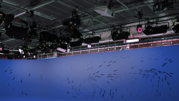 A photo from a weather film studio, the top half is film equipment, the bottom half is a bluescreen covered in arrows