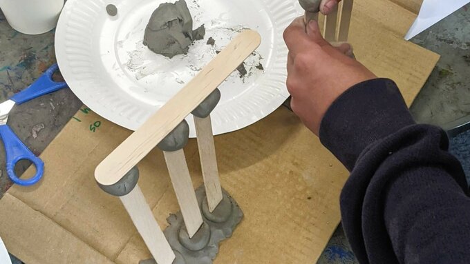 Hands play with clay and other materials.