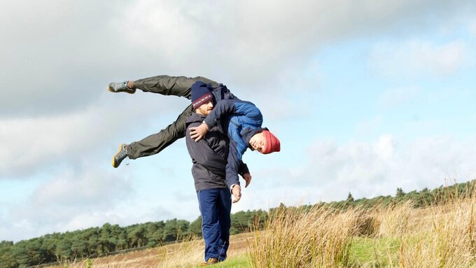 One person lifting another from the shoulder outdoor in a field
