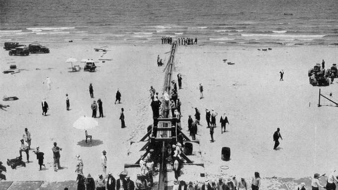 A black and white photo of workers in front of the pipeline as it recedes into the mediterranean sea.