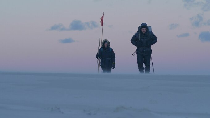 A couple dressed in warm clothes seen from afar in a seaside landscape at dawn