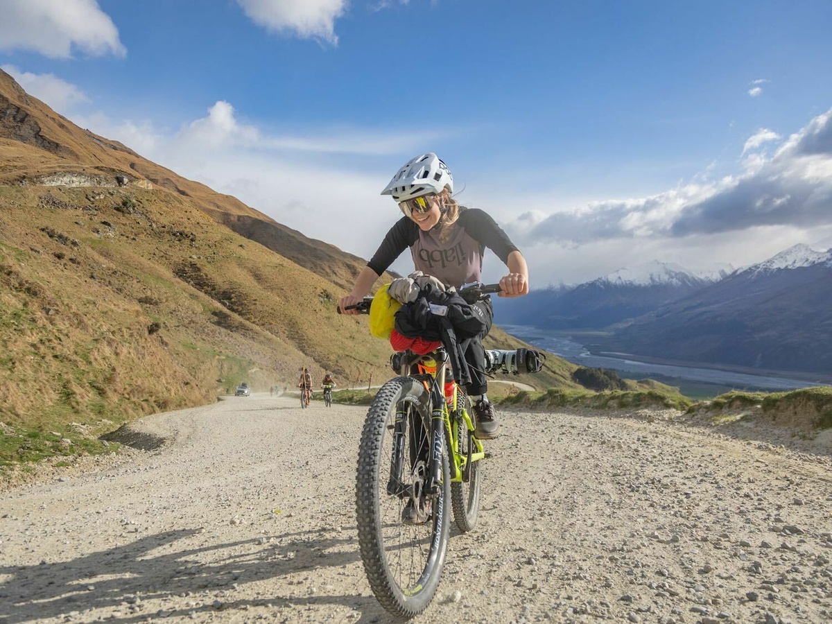 A person cycling an off road bike down a gravel path in a dramatic landscape.