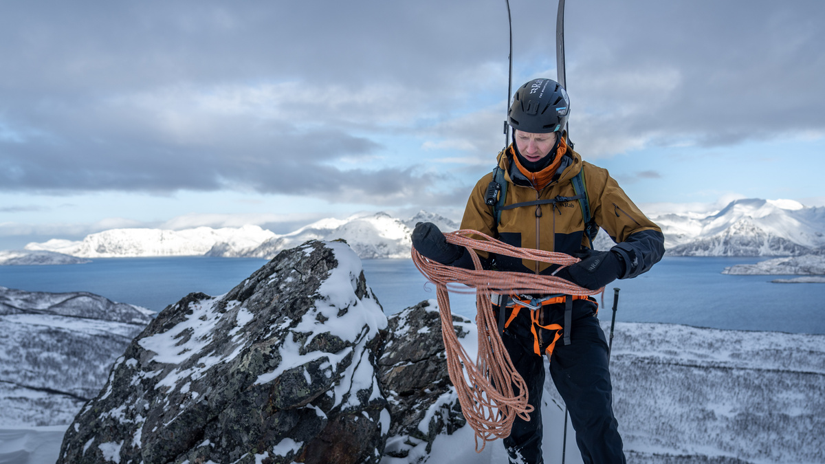 A skier at the top of a mountain overlooking snow mountain tops.