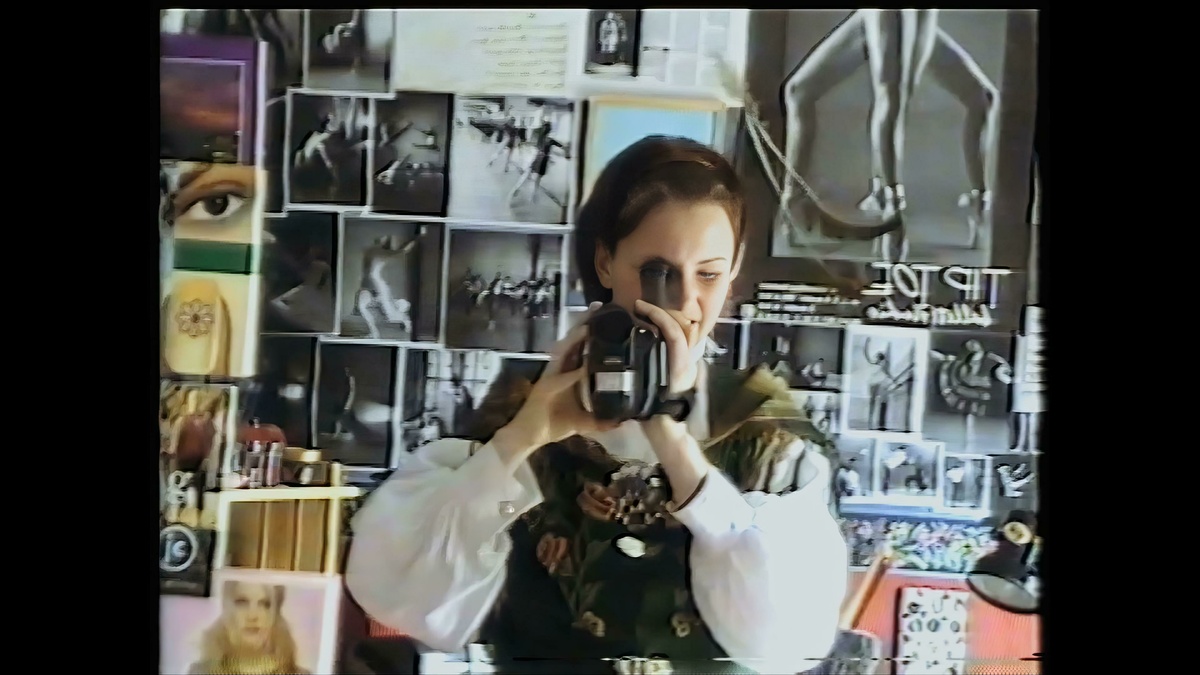 A still of a woman wearing medieval dress pointing a camcorder at a mirror.