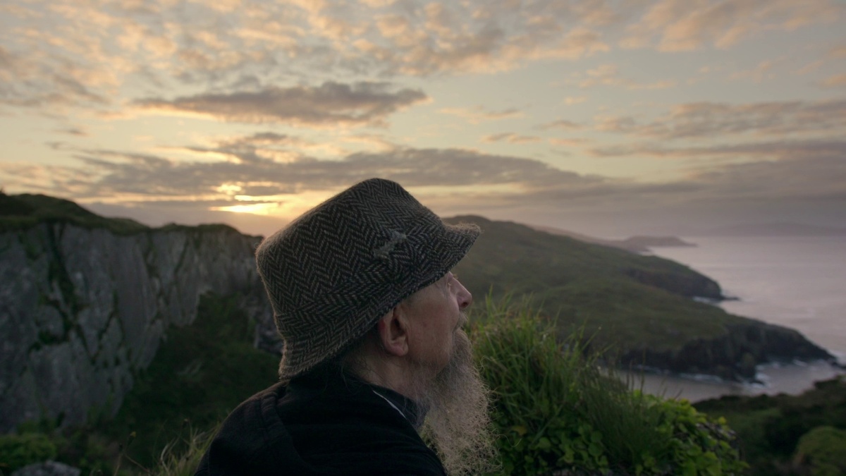 An older man looking across a sweeping coastline.