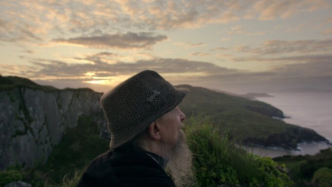 An older man looking across a sweeping coastline.