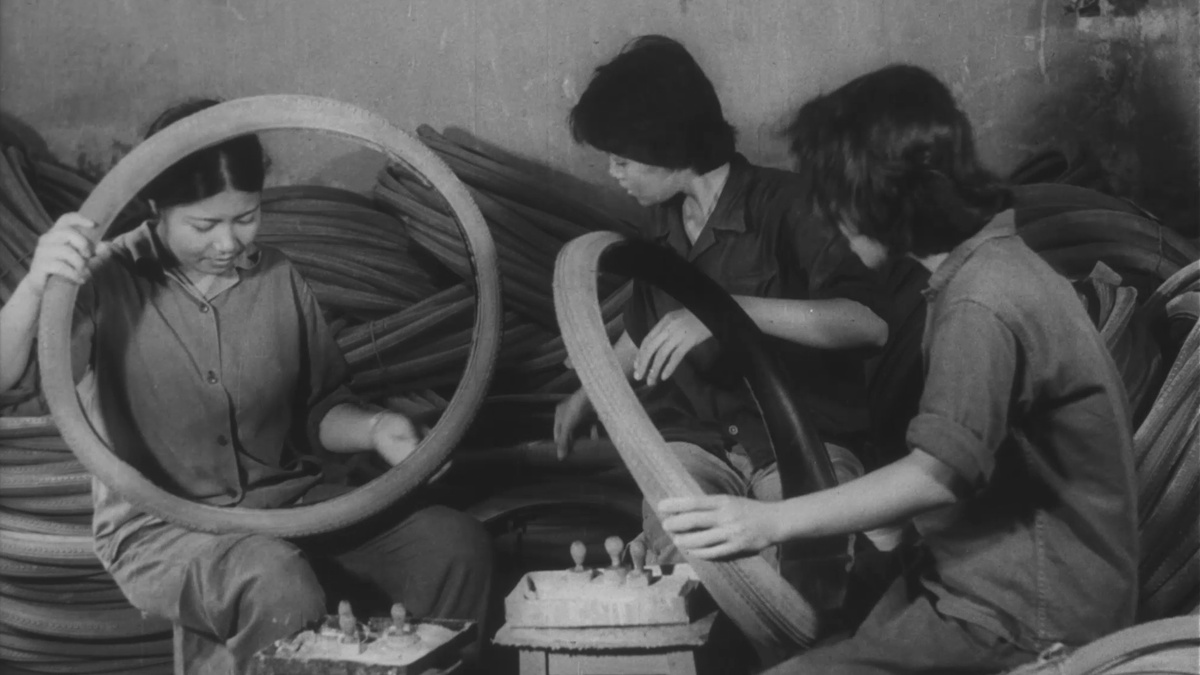 Three women sitting down, inspecting bicycle tyres.