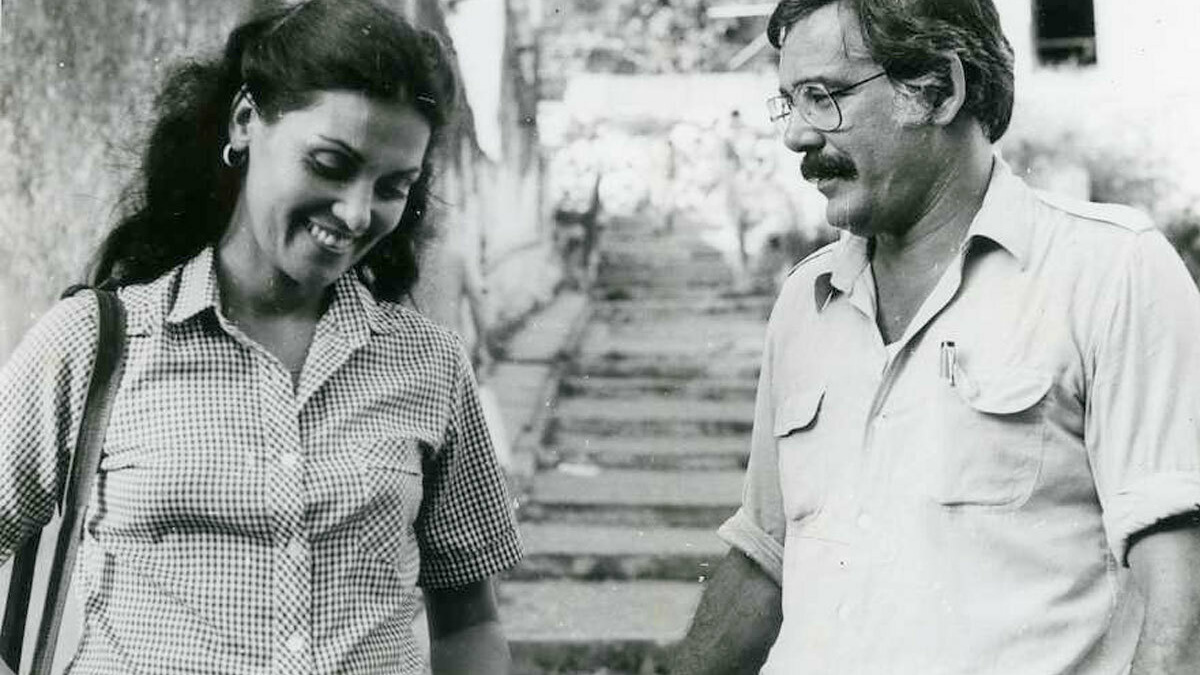 A woman and man stand at the bottom of some stairs. The woman is smiling.