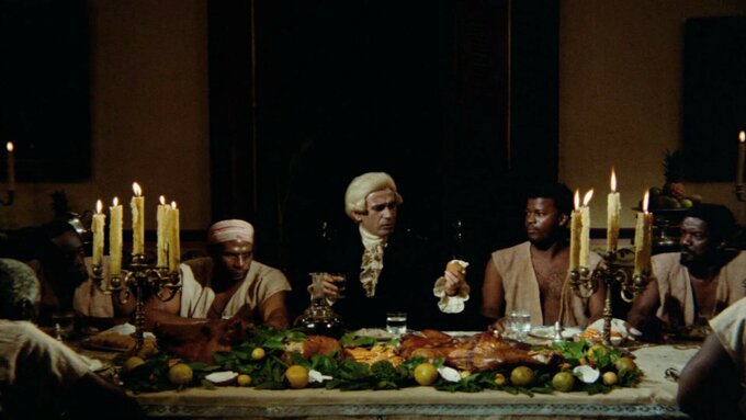 An aristocrat with a wig sits at the centre of a feast, surrounded by slaves