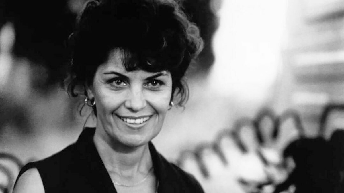 A woman with earrings is smiling to camera