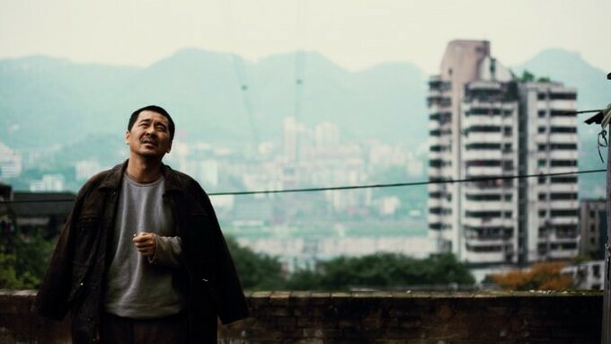 A person stands on the left of an old tower block.