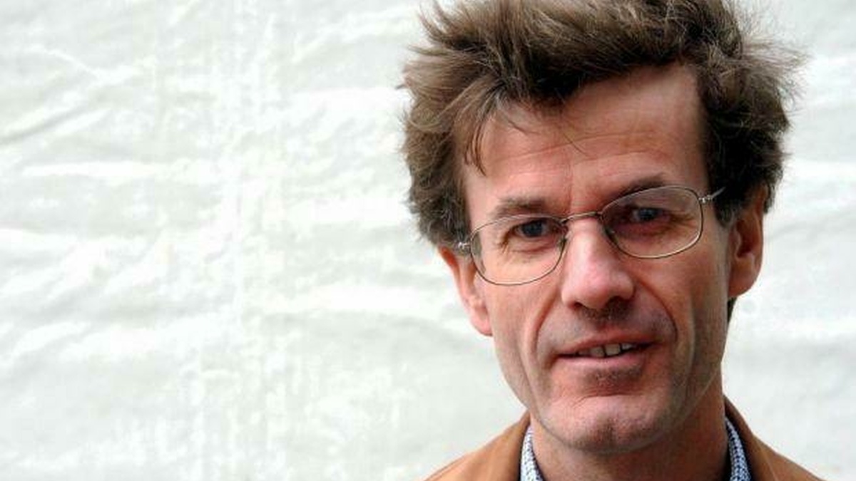 Headshot of Robert Crawford, a pale skinned professorial man with glasses and messy windswept brown hair.