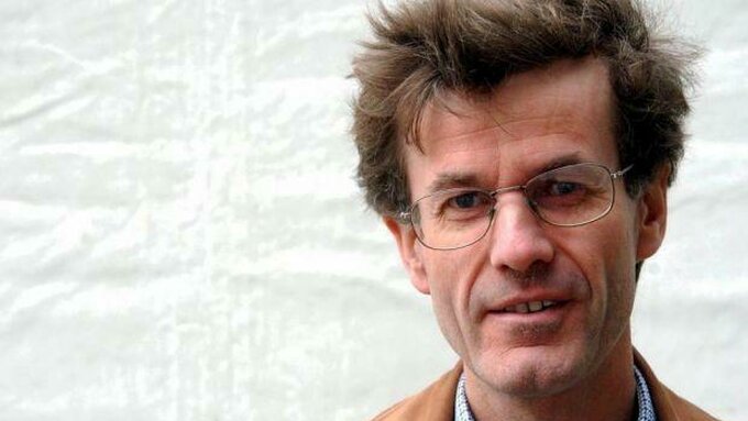 Headshot of Robert Crawford, a pale skinned professorial man with glasses and messy windswept brown hair.