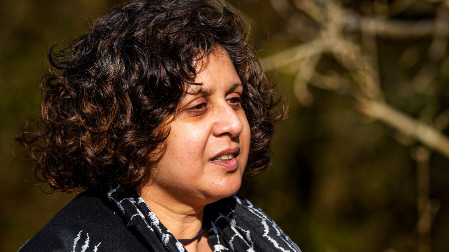 A headshot of Anthony in a wooded area. They have brown skin and dark curly hair, they have a keffiyeh around their neck