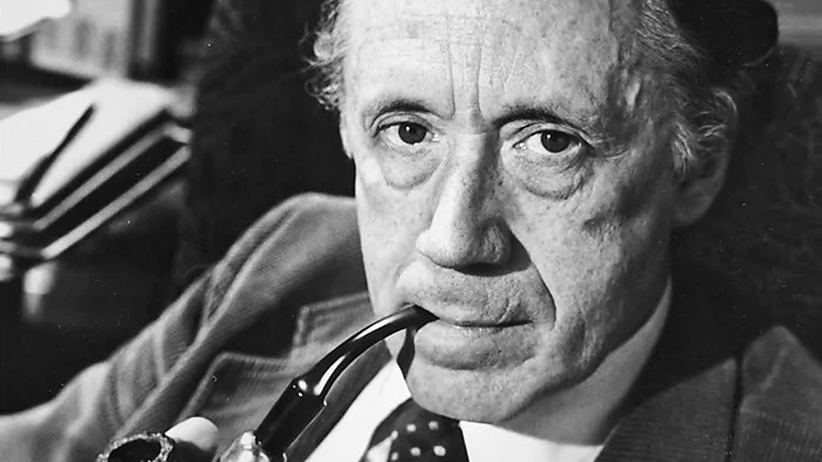 Black and white photo of a distinguished looking gentleman, smartly dressed in 1960s style and smoking a pipe.