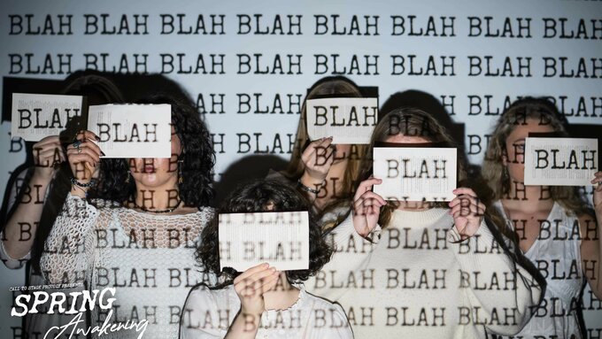 6 people wearing plane white T-shirts and covering their faces with paper, the word "BLAH" is projected onto them.