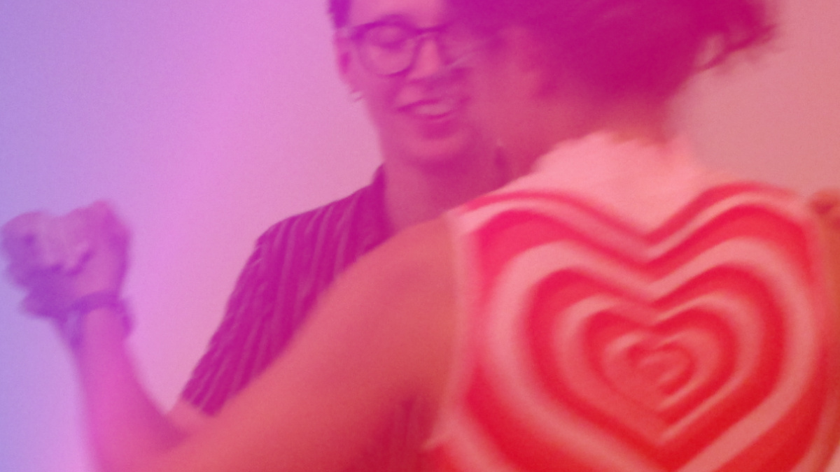 The image is of two people dancing tango. The image is in shades of red, pink and purple.