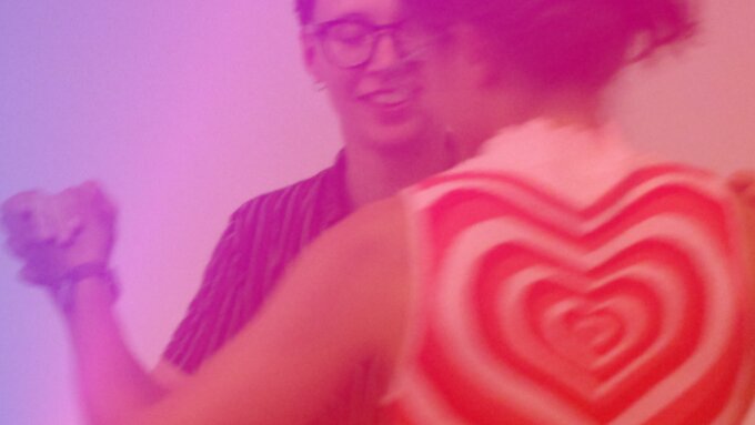 The image is of two people dancing tango. The image is in shades of red, pink and purple.