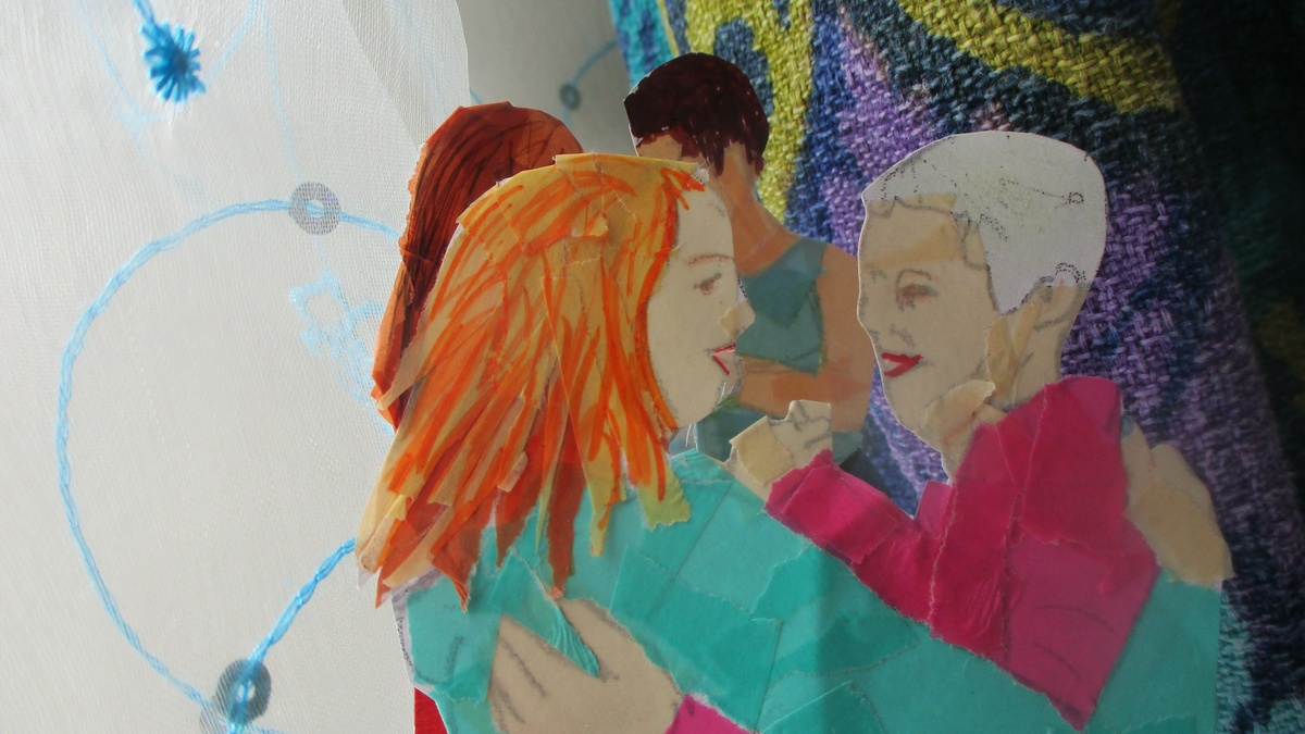 A paper cut out illustration of a couple dancing tango. 1 has white hair & pink clothes and the other has red hair.