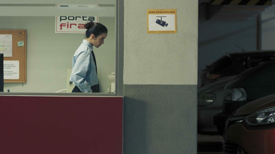 A view of a security through a window. She is looking at something that we can't see behind a wall.