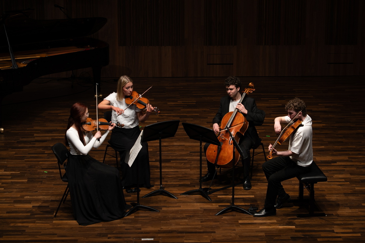 4 violinists and a chellist performing on stage.