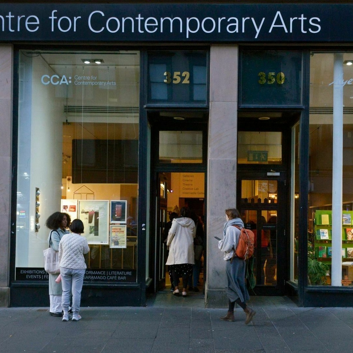 A photograph of the front of CCA with the door open and people entering the building.