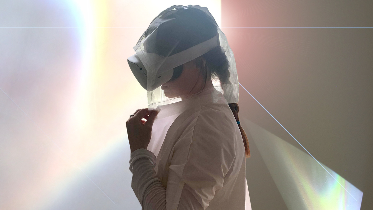 A person stands with a white VR mask on