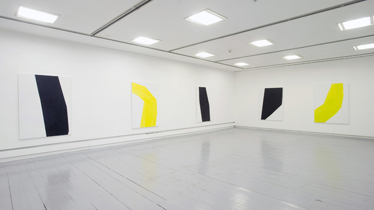 A photograph of CCA's Intermedia gallery, it shows a white room with large abstract paintings in yellow and black.