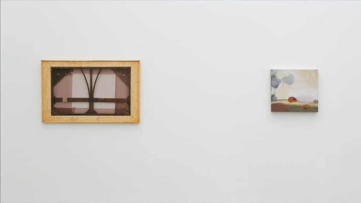 A white wall with two paintings hung.