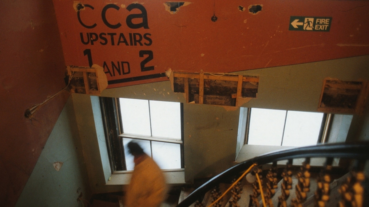 A photograph of the old entrance to the CCA performance space, depicting a staircase and signage for CCA Upstairs.