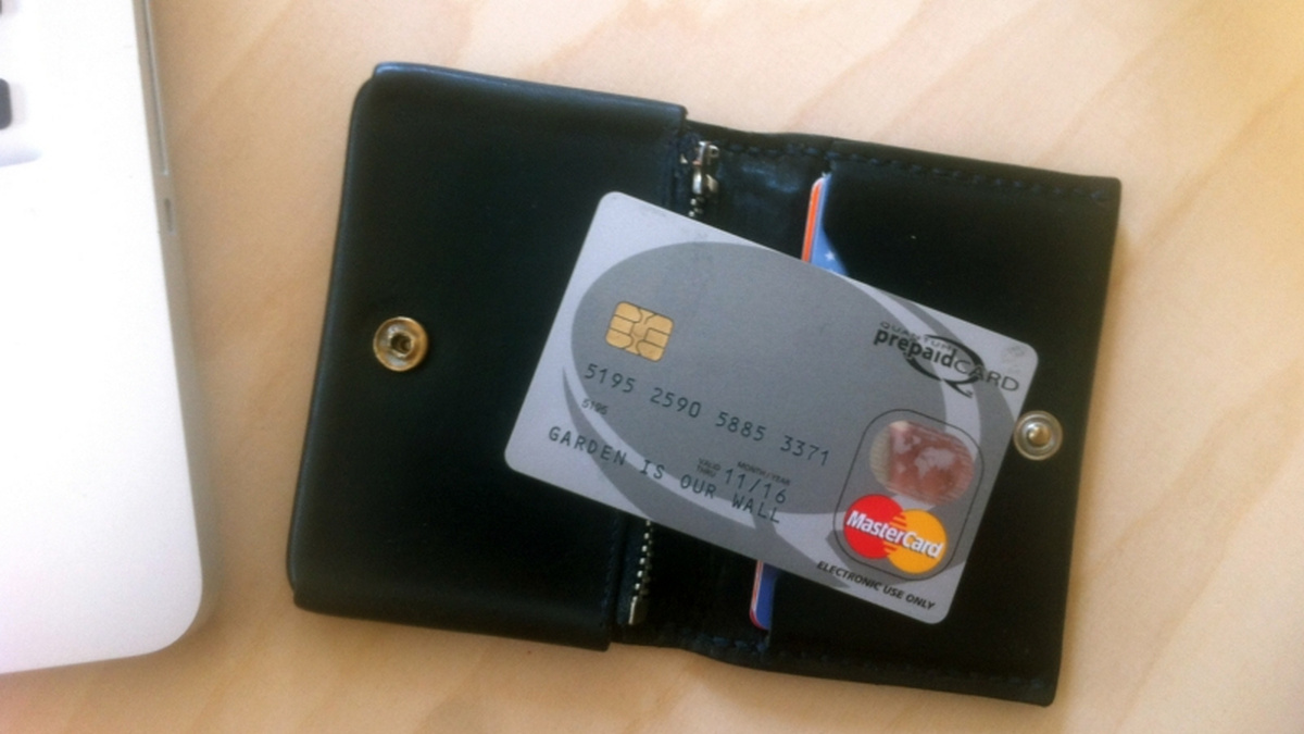 A leather wallet sits open, with a credit card on top of it.