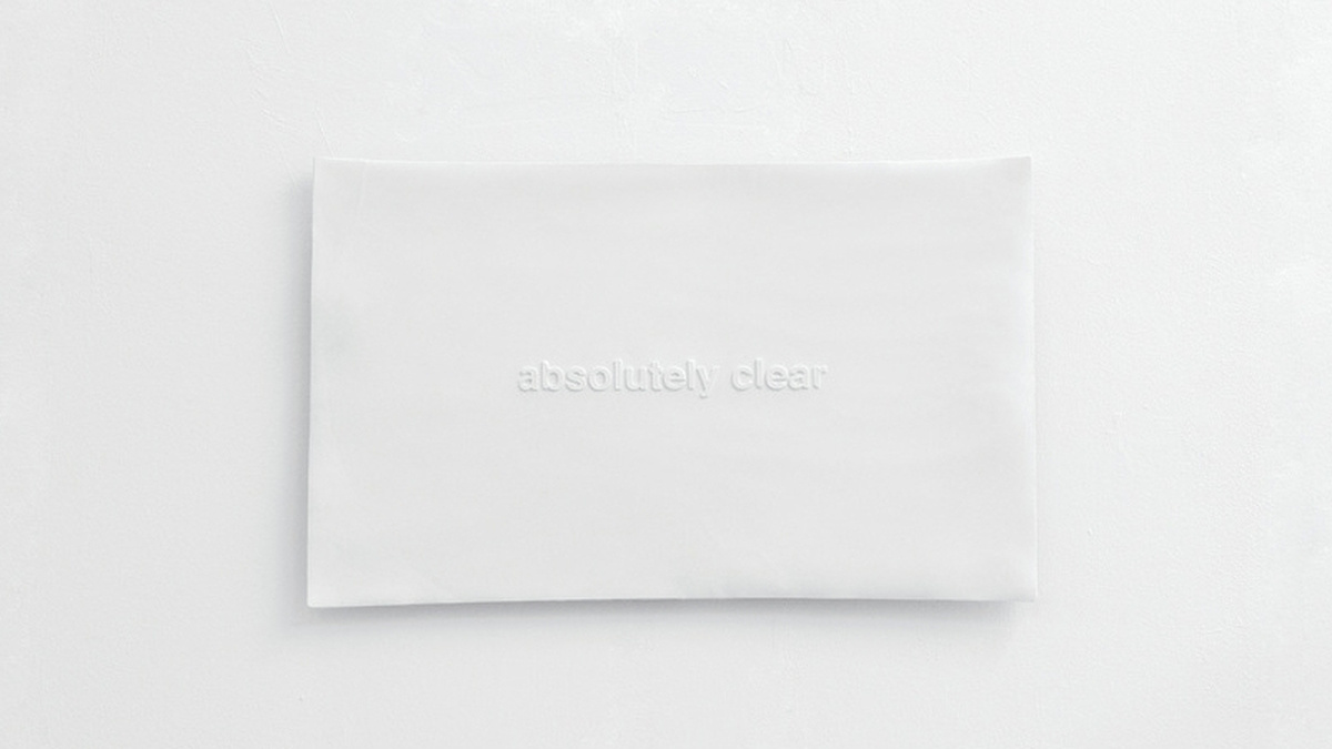A white block with white lettering reading "absolutely clear" lies on a white surface.