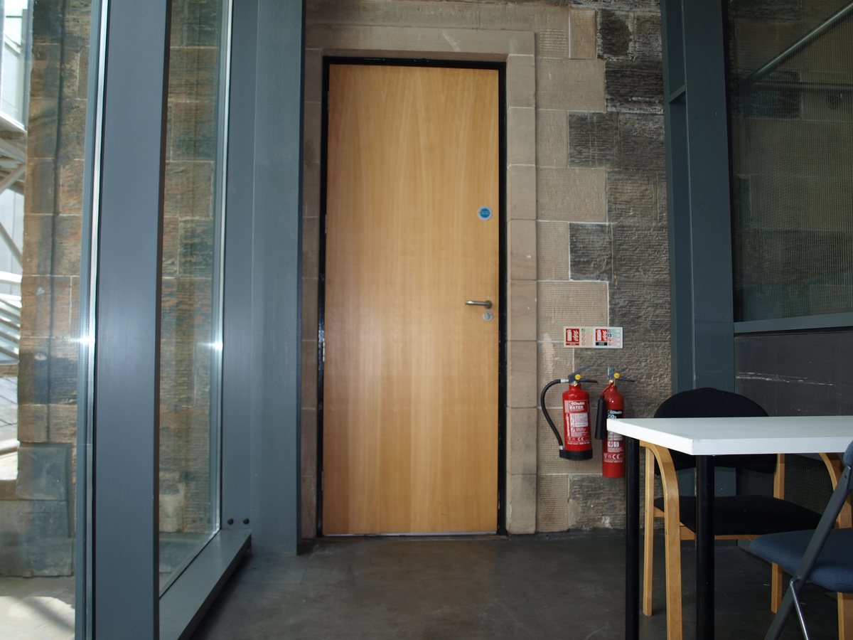 A photograph of the back entrance of the CCA featuring, featuring a wooden door.