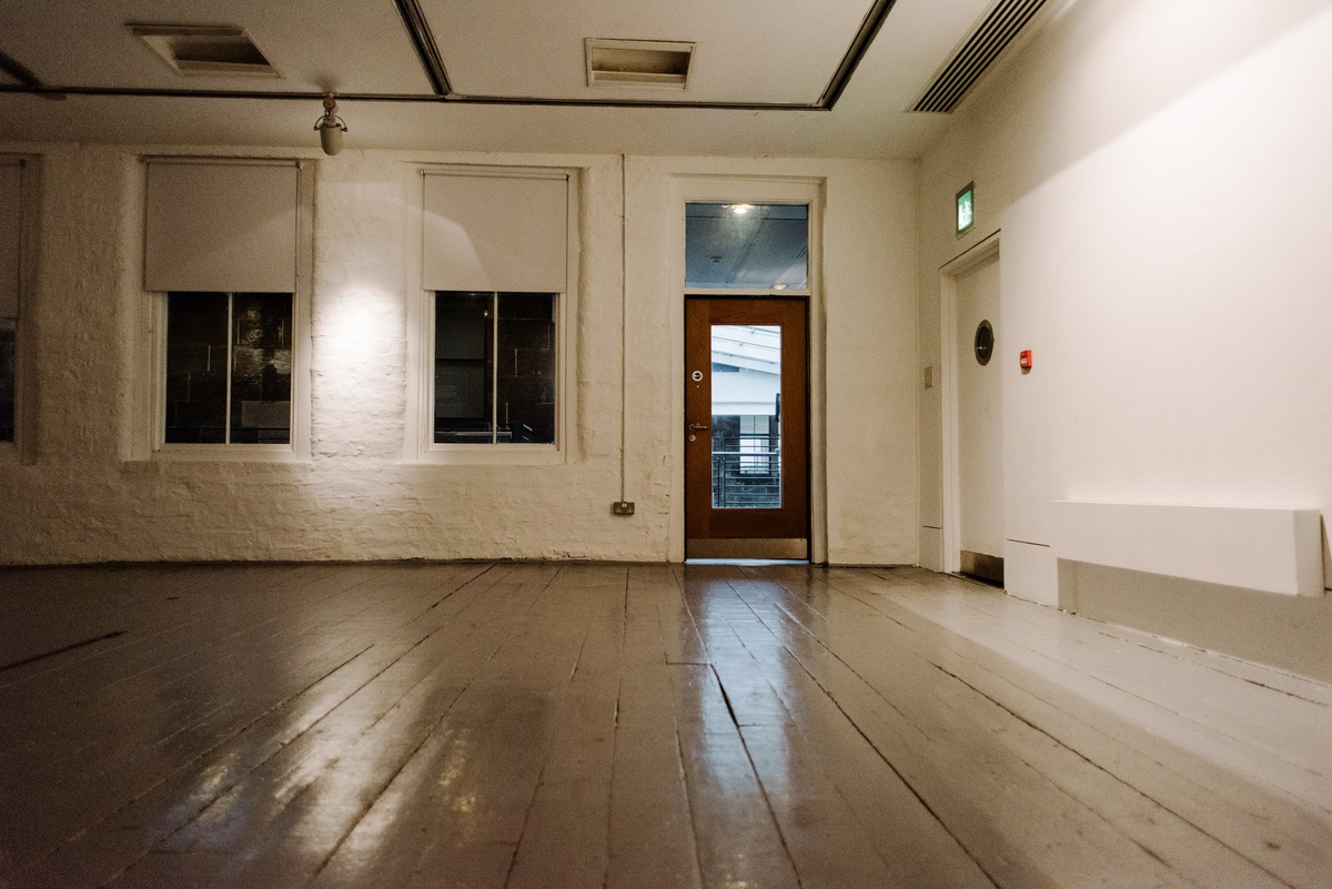 A photograph of the CCA intermedia gallery, a white room with two windows and a door.