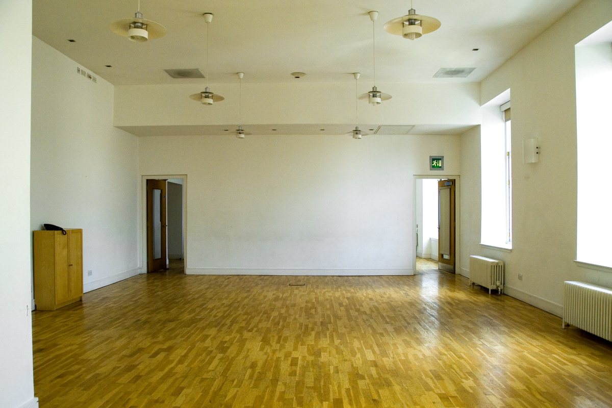 A photograph of the CCA clubroom, a white room with laminated wooden flooring.