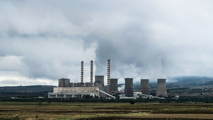 A Coal fired Power Station in a barren field spewing pollution into the air.