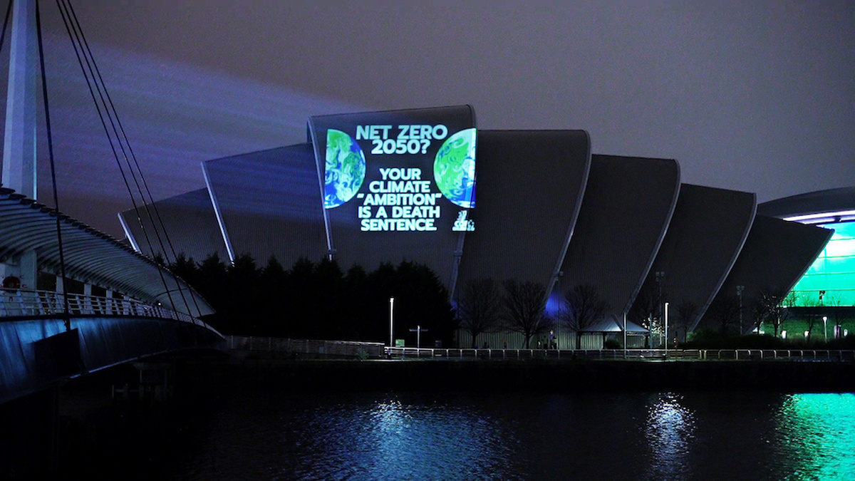 Projection onto COP26 venue that reads "Net Zero 2050? Your Climate Ambiton is a death sentence".