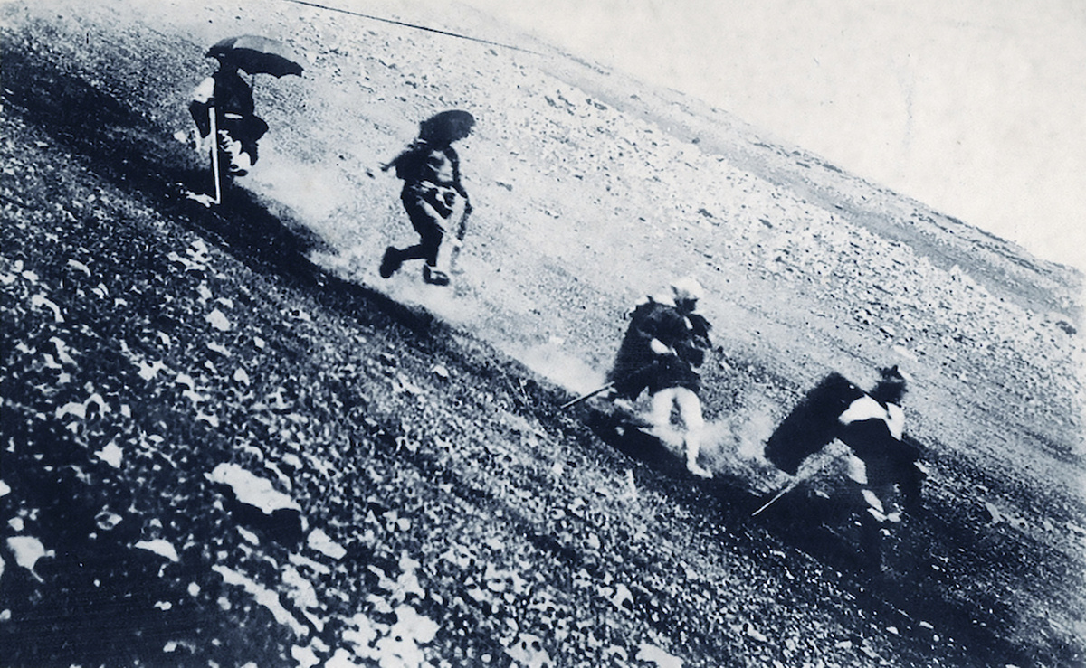 Monochromatic image of people descending a rocky mountain slope.