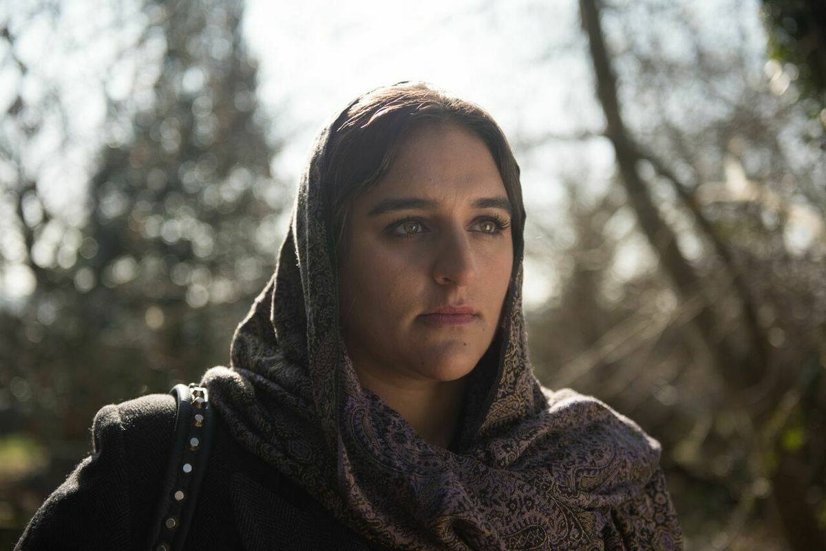 A portrait of a young woman standing outside wearing a hijab.