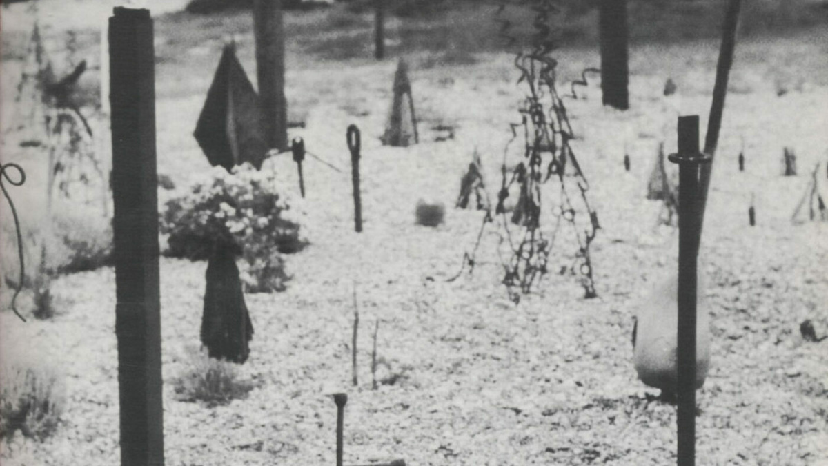 A black and white photograph of abstract sculptures by Derek Jarman on a beach scene, covered in a thin layer of snow.
