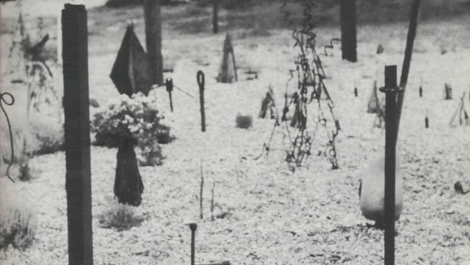 A black and white photograph of abstract sculptures by Derek Jarman on a beach scene, covered in a thin layer of snow.
